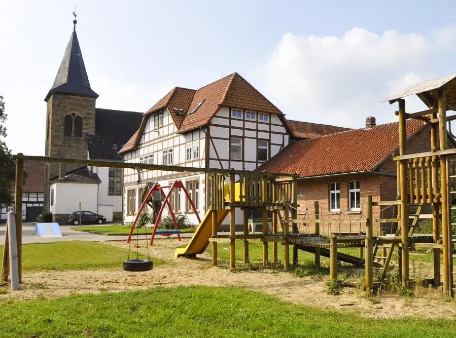 Bund der Caritasstiftungen im Bistum Hildesheim BdC Kinder- und Jugendhilfe: Klettergerüst, Fachwerkhaus und Kirche in Henneckenrode