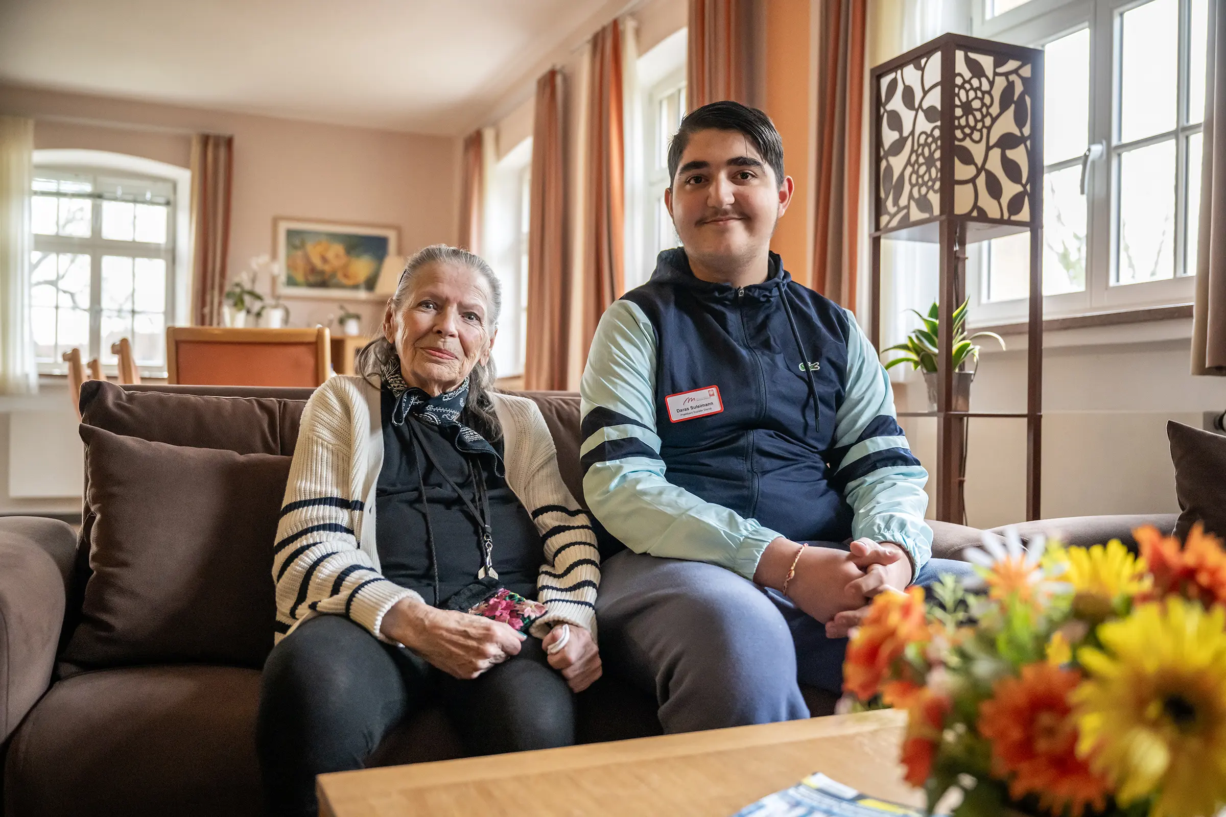 Bund der Caritasstiftungen im Bistum Hildesheim BdC Seniorenhilfe: Ehrenamtlicher Helfer sitzt mit Seniorin auf Sofa