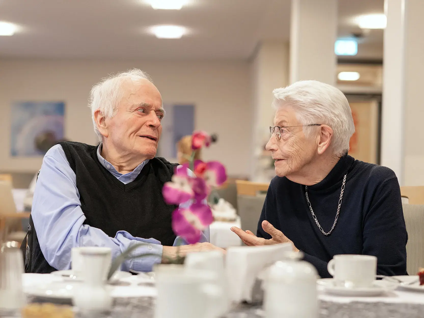 Bund der Caritasstiftungen im Bistum Hildesheim BdC Seniorenhilfe: Seniorin und Senior führen Gespräch im Speisesaal klein
