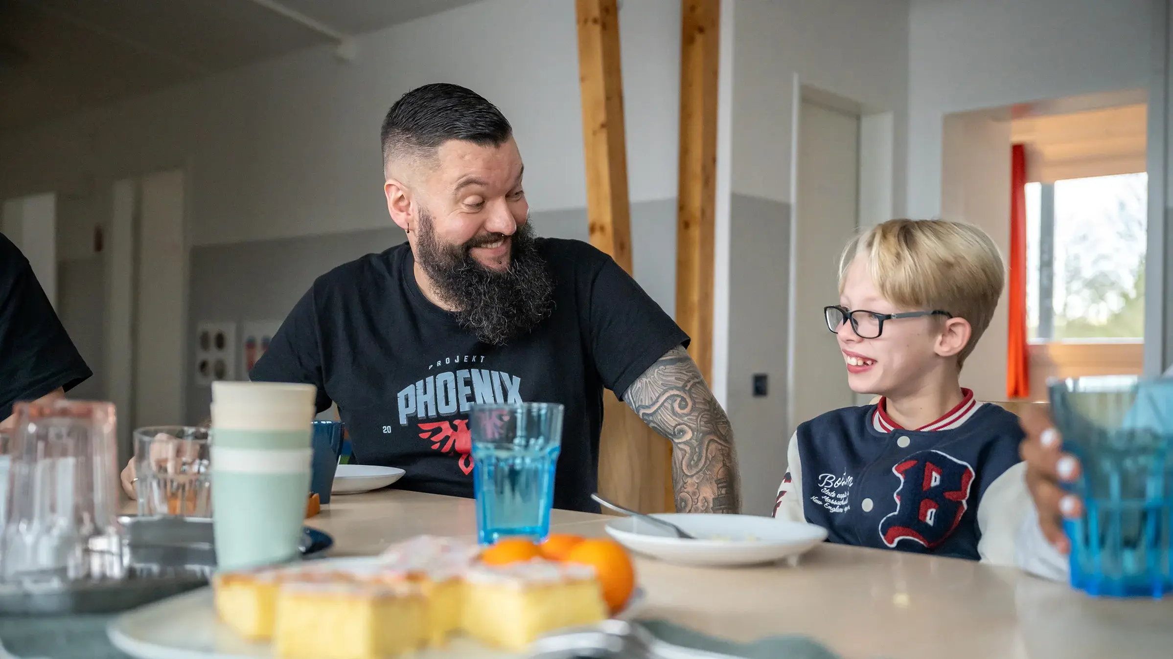 Bund der Caritasstiftungen im Bistum Hildesheim BdC Kinder- und Jugendhilfe: Mitarbeiter wendet sich an Jungen am Esstisch mittel