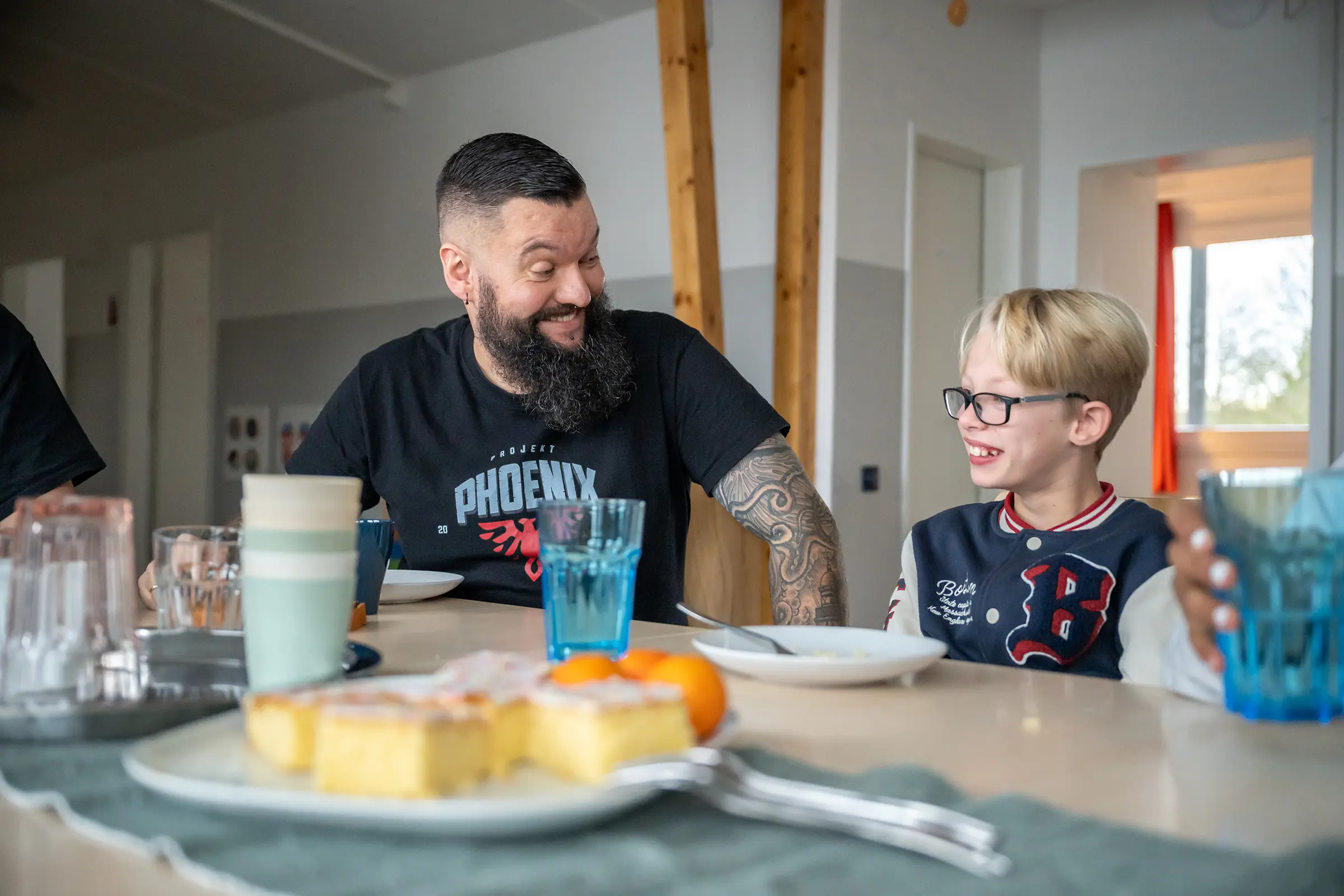 Bund der Caritasstiftungen im Bistum Hildesheim BdC Kinder- und Jugendhilfe: Mitarbeiter wendet sich an Jungen am Esstisch mittel